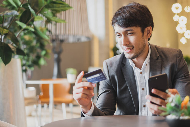 Asian businessman using credit card and mobile phone for online financial payment and shopping - Photo, Image