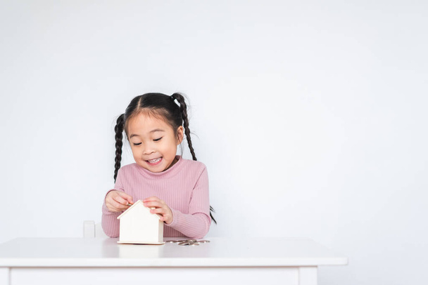 Asiatique fille enfant, insérer pièce de monnaie à la boîte de dépôt, concept d'économie d'argent sur fond blanc - Photo, image