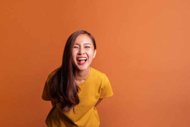 Молодая азиатка портрет на оранжевом фоне, улыбка счастливый студийный снимок - Фото, изображение