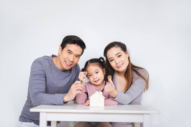 Щаслива азіатська сім'я вставляє монети в коробку за білим фоном для економії концепції грошей - Фото, зображення