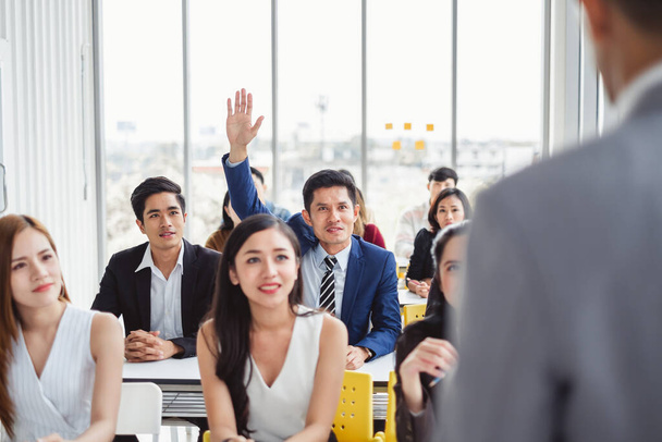 Homem de negócios levantando a mão para pedir orador para pergunta e conceito de resposta na sala de reuniões para seminário
 - Foto, Imagem