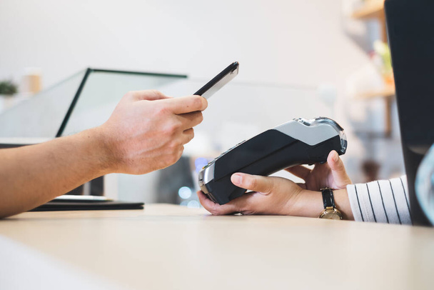 Πελάτης που χρησιμοποιεί το τηλέφωνο για την πληρωμή στον ιδιοκτήτη στο εστιατόριο cafe, χωρίς μετρητά τεχνολογία και πιστωτική κάρτα έννοια πληρωμής - Φωτογραφία, εικόνα