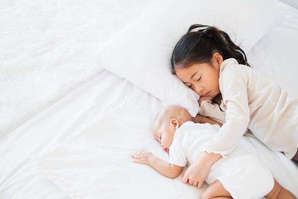 ásia bonito menina dormir com bebê no branco cama - Foto, Imagem
