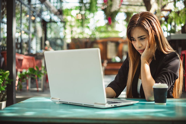 Молодая красивая азиатская женщина чувствует боль, усталость, головную боль, и подчеркнул, работая с ноутбуком в кафе кафе, винтажный тон, концепция офисного синдрома - Фото, изображение