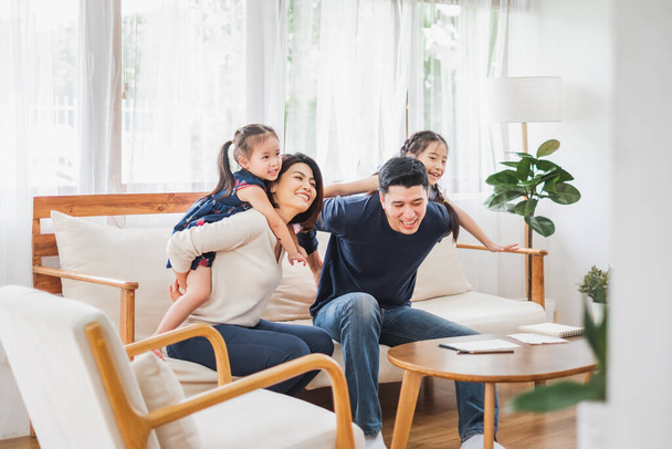 Szczęśliwa azjatycka rodzina bawi się razem na kanapie, w domu pokój dzienny - Zdjęcie, obraz