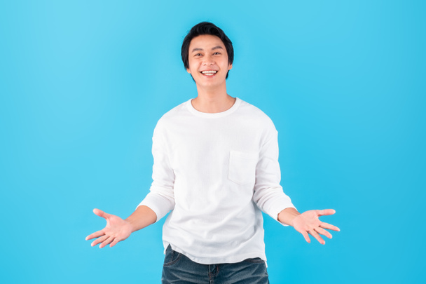 Joven hombre asiático feliz mano abierta palma sentir sorpresa / shock / asombro / wow sobre fondo azul. - Foto, Imagen