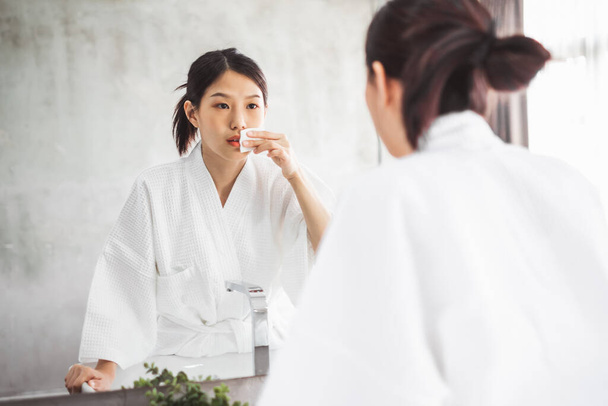 Aynanın, cilt bakımının ve kozmeti 'nin yüzünü temizleyen Asyalı kadın. - Fotoğraf, Görsel