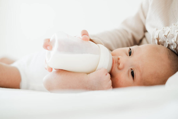 Мать кормит азиатского ребенка бутылкой молока - Фото, изображение