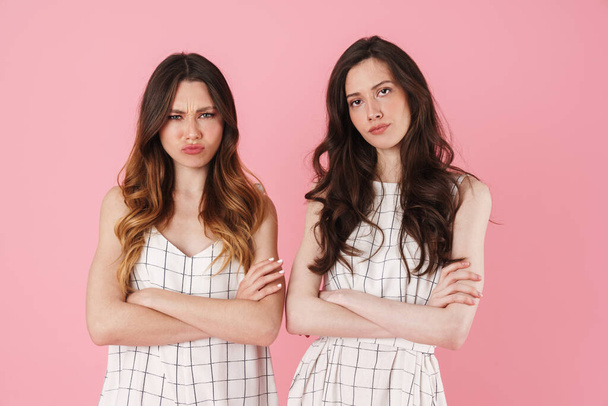 Image of displeased nice women posing at camera with hands crossed isolated over pink background - Фото, зображення