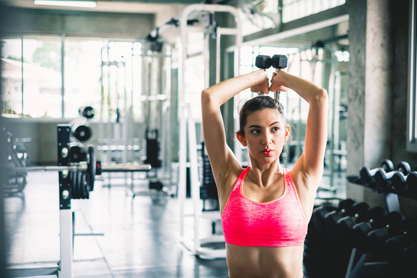 Spor salonunda ağırlık çalışması için dambıl kaldırarak kadın egzersizi - Fotoğraf, Görsel