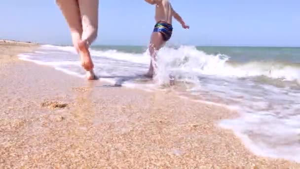 Äiti ja poika juoksevat mielellään rannalla. Käsitteen rentoutumista ja viihdettä merellä sekä lastenhoitoa. Resort hauskaa meren rannalla - Materiaali, video