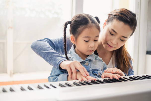 Asiática joven pianista profesor enseñanza chica niño estudiante a jugar piano, música educación concepto - Foto, imagen