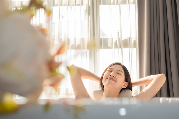 Молода приваблива азіатка купається в ванній кімнаті, масажуючи ідеальну шкіру. - Фото, зображення