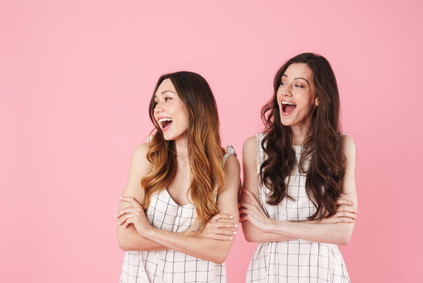 Image of joyful caucasian women laughing while posing with arms crossed isolated over pink background - Photo, Image