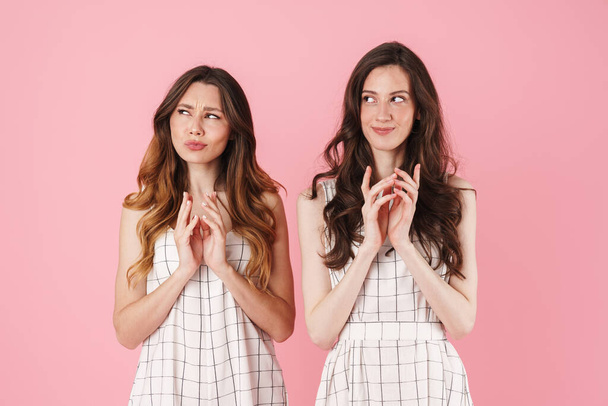 Image of clever young beautiful women thinking and looking aside isolated over pink background - Foto, immagini