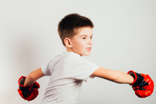 serious boy in boxing gloves training and boxing on grey background - Fotografie, Obrázek