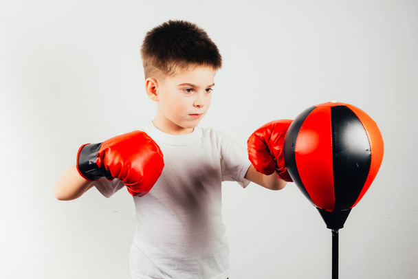 serious boy in boxing gloves training on grey background - Fotoğraf, Görsel