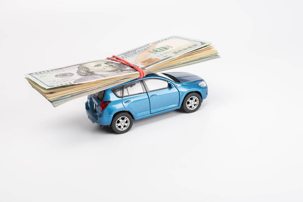 toy car carrying dollar banknotes on white background - Foto, Imagen