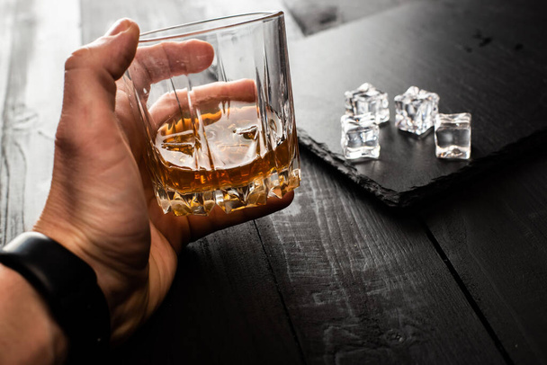 cropped shot of man holding glass of whiskey with ice cubes - Foto, imagen