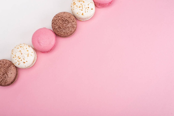 Nahaufnahme von süßen leckeren Macarons auf rosa und weißem Hintergrund - Foto, Bild