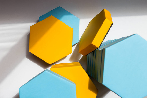 Ένα κοντινό όμορφο μπλε και κίτρινο εξάγωνο κουτιά του παρόντος στο λευκό φόντο. Θέση για κείμενο. Κενό κέντρο. Στο πάνω μέρος. Επίπεδη. Κοπάδι - Φωτογραφία, εικόνα