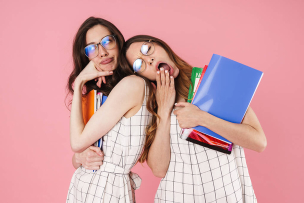 Image of tired student women yawning posing with exercise books isolated over pink background - Φωτογραφία, εικόνα