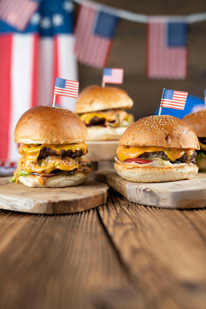 Fourth of July celebration. American flag and decorations. Burgers on rustic wooden table. - Photo, Image