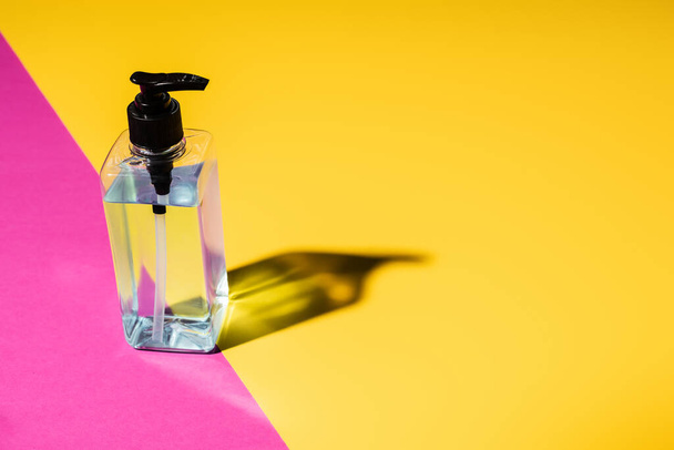 disinfectant in transparent bottle on pink and yellow with shadow - Foto, Imagem