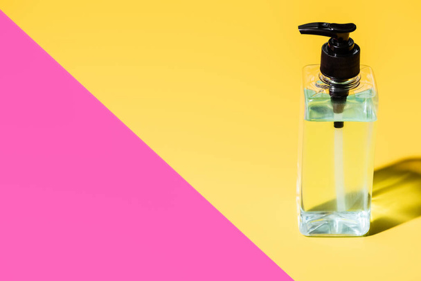 antiseptic liquid in transparent bottle on pink and yellow with shadow - Foto, afbeelding