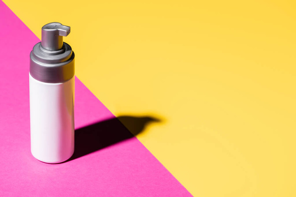container with cosmetic lotion on pink and yellow with shadow - Fotoğraf, Görsel