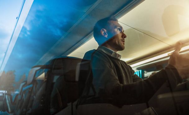 Kaukasische Männer und seine Busreisen. Thema öffentliche Verkehrsmittel. Passagier hinter Busfenster spricht mit jemandem.  - Foto, Bild