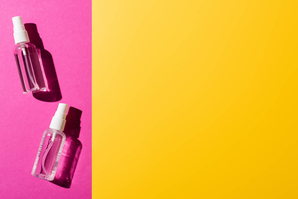 vista superior de botellas de spray transparentes con desinfectante en rosa y amarillo
 - Foto, Imagen