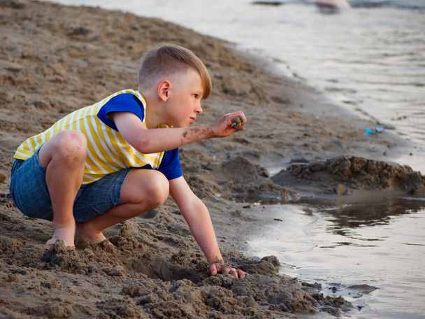 Junge spielt am Strand in Wassernähe mit Sand - Foto, Bild