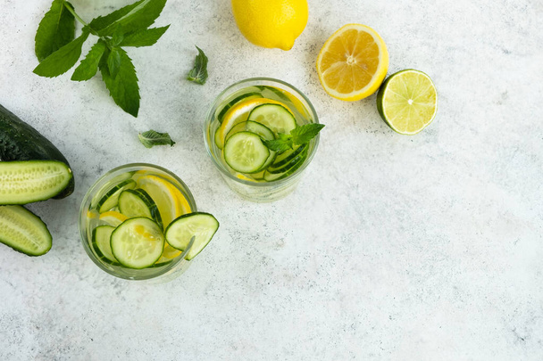 Komkommer, citroen en limoen verfrissend drankje. Zomer cocktail op keukentafel. Bovenaanzicht, flat lay, kopieerruimte - Foto, afbeelding