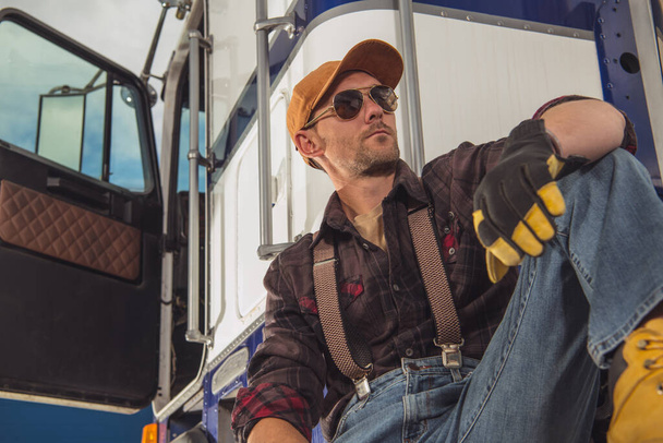 Industria dei trasporti. caucasico camionista nel suo 40s relax accanto al suo semi camion durante necessario lavoro pausa in continuo guida
. - Foto, immagini