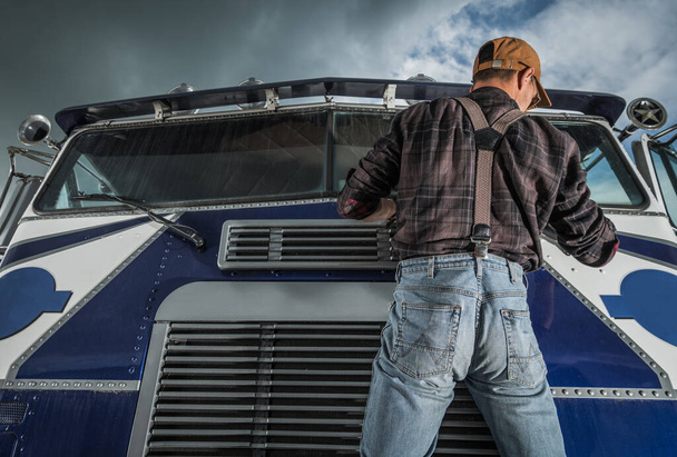 Conductor comercial caucásico en sus 40 años revisando limpiaparabrisas de camiones en su vehículo. Camionero y su trabajo. Semi Mantenimiento
. - Foto, imagen