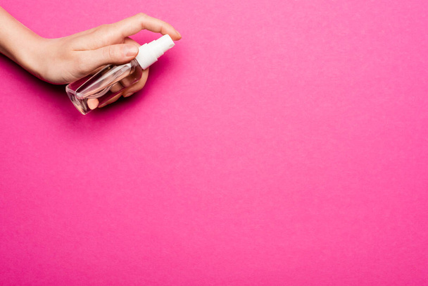 partial view of woman spraying hand antiseptic on pink - Foto, afbeelding