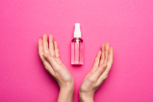 partial view of female hands near spray bottle with hand sanitizer on pink - Photo, Image