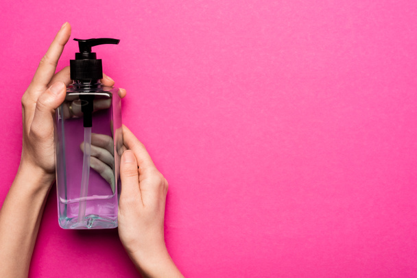 cropped view of woman holding bottle with hand sanitizer on pink - Photo, Image