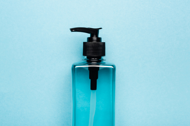 top view of hand antiseptic in transparent bottle with dispencer on blue - Foto, Imagen