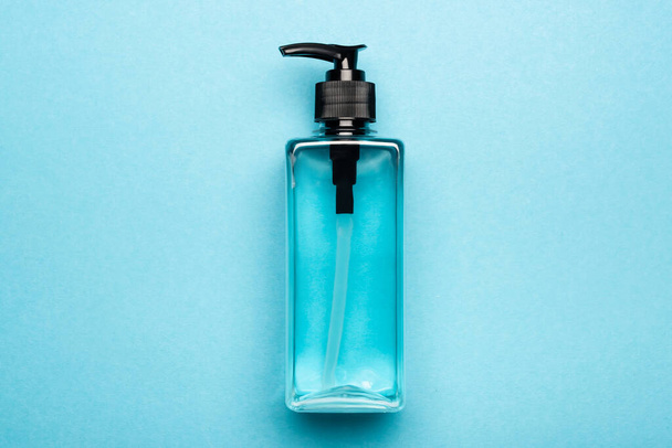 bovenaanzicht van antiseptische vloeistof in transparante fles op blauw - Foto, afbeelding