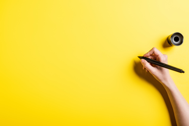 bijgesneden weergave van ontwerper houden stylus in de hand op geel  - Foto, afbeelding