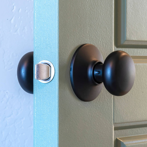 Quadrado Fechar-se de uma maçaneta redonda da porta preta instalada em uma porta interior cinzenta painel
 - Foto, Imagem