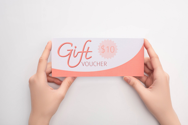 Top view of woman holding gift voucher with 10 dollars sign on white background - Фото, зображення