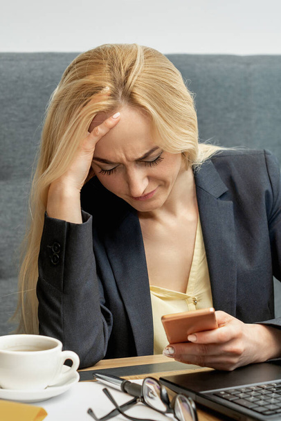 Frustrata giovane donna che sembra sorpreso di lavorare su smartphone a casa ufficio
. - Foto, immagini