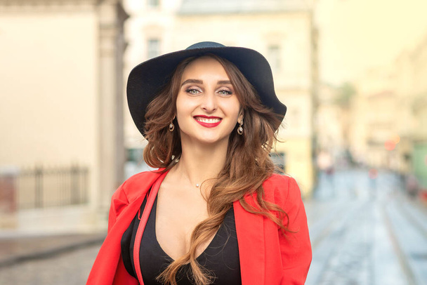 Outdoor portrait of young elegant fashionable woman wearing trendy hat walking in street of European city. - Photo, Image