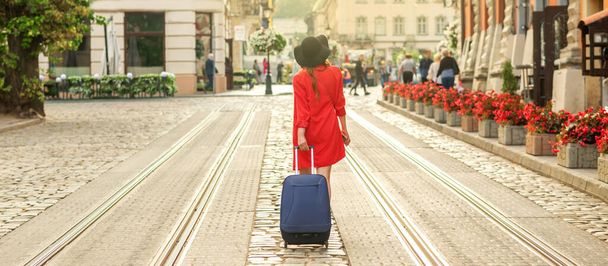 Gyönyörű fiatal üzletasszony sétál a villamos pályán egy város utcájában kék utazási táska. - Fotó, kép