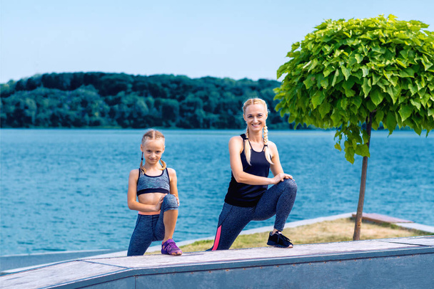 Portrait of mother and child in sport style clothes on the shore of the lake. - Fotografie, Obrázek