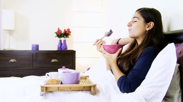 glückliche junge Frau frühstückt im Bett - Filmmaterial, Video