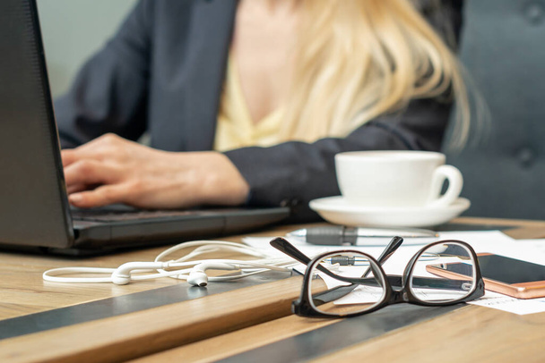 óculos com café na mesa de escritório sobre fundo trabalhador de negócios feminino
. - Foto, Imagem